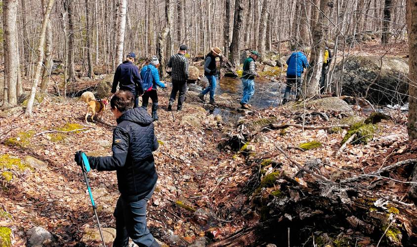 The Harris Center’s veterans hiking group, with Jennifer Whitney of the Keene Veterans Center, in black jacket as “caboose,” crosses a stream on Mount Skatutakee. 