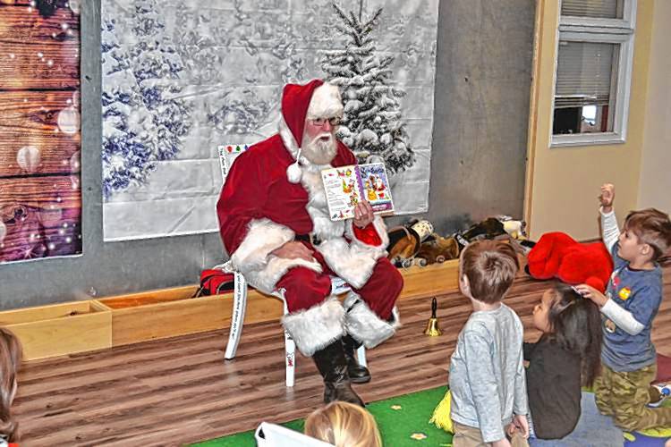 John Stone, as Santa, reads to children at Jaffrey Public Library.