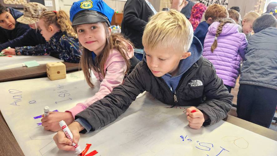 Ava Dentesano, left, and Baylor Lehtonen add their artwork to thank you banners for first-responders in the region.