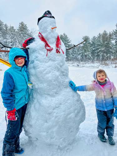 Kai and Darci Curtis pose next to their 6-foot, 5-inch snowman at their home in New Ipswich.