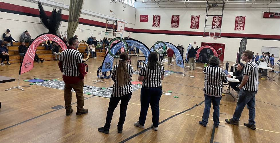 Drones competition referees survey the scene in the gym at Great Brook School.