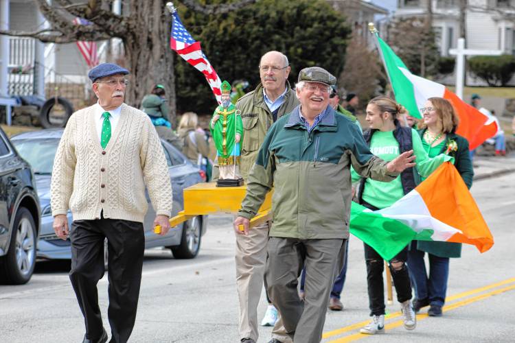 Bill Weibel, Bob Schaumann and John McCarthy carry the statue of St. Patrick down Main Street.