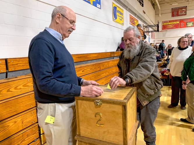 Rindge resident Richard Mellor casts a vote on an amendment calling for a cut to the proposed school budget while Moderator Bob Schaumann mans the ballot box.