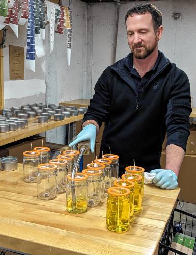 Grey Horse Candle Company co-owner Brian Cannon demonstrates the jar-filling process.