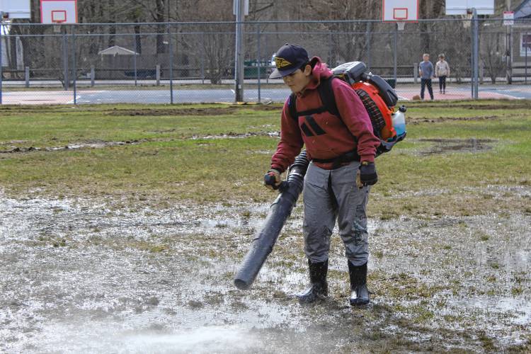 Isaac Oliveira of New Ipswich uses a leaf-blower to disperse pooled water from the field, helping it to dry out in time for the upcoming Little League season.