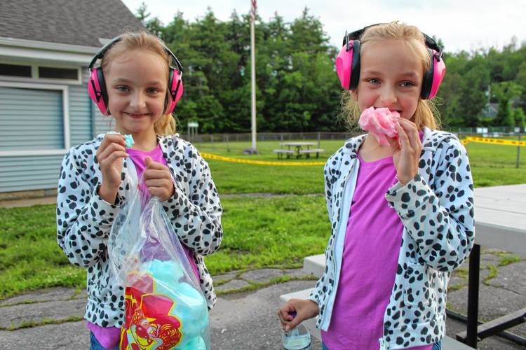 Twins Hailey and Ruby Antos, 8, of Greenville, munch on cotton candy while sporting mufflers in preperation for fireworks.