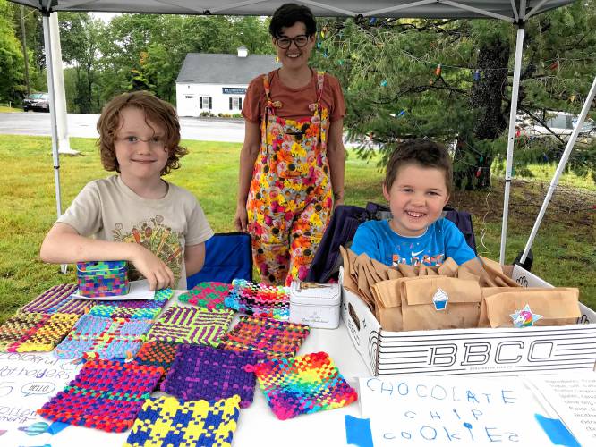 Rowan and Robbie Simmons, with their mother Beth Simmons, sell potholders and bags of homemade chocolate chip cookies.