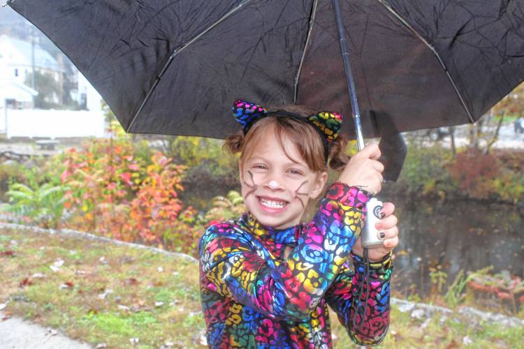Amelia Anderson, 6, of Deering, keeps her colorful cat costume dry under an umbrella.