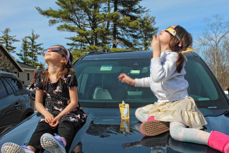 Riya Virostko of Townsend, Mass., and Malani Nunez of Westminster get a good view from the hood of a car.