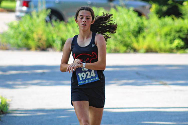 Olivia Richard of Rindge, who finished third overall, was the first female finisher and the first 17-and-under finisher, checks her time as she crosses the finish line.