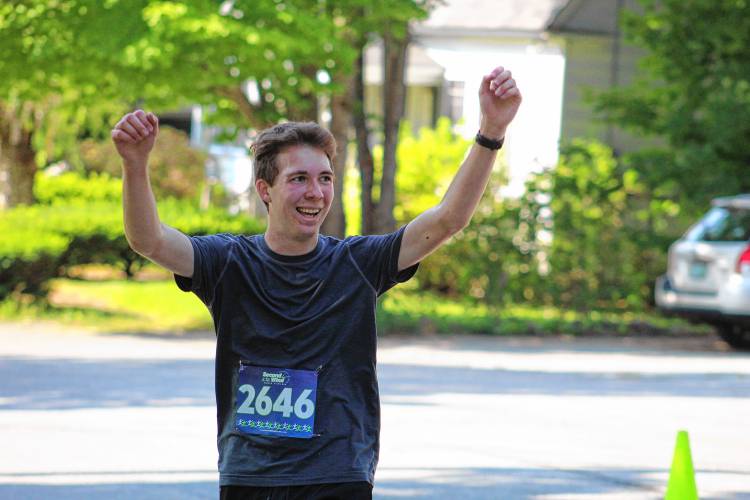 Trayton Chapman of Rindge, who finished fourth overall and was the frist male 17-and-under finisher, raises his arms in celebration as he crosses the finish line.