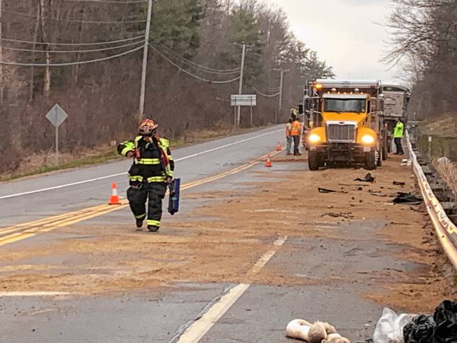 A Jaffrey Department of Public Works dump truck helps spread sand to contain a fuel spill on Route 202 following a crash.