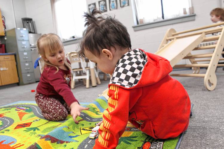 Mya Cote and Michael Dibble use a playmat laid out like a streetmap for Matchbox cars in the Conant day care playroom.