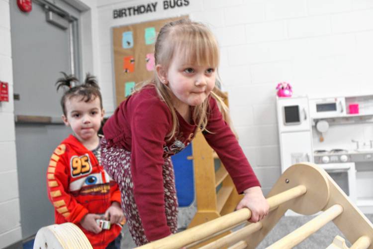 Mya Cote and Michael Dibble make a determined climb to the top of a wooden slide in the playroom.
