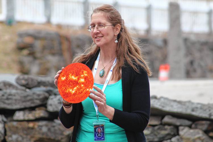 Eclipse ambassador Susan Rolke holds up an image of the sun, relative to the size people see it, to show children how it only takes a single one of their fingers to cover the entire image.