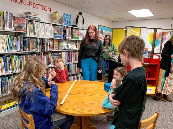 Eclipse ambassador and Franklin Pierce University student Raven Groblewski works with children at the Ingalls Memorial Library in Rindge to show the relative size and distance between the Earth’s moon and the sun.