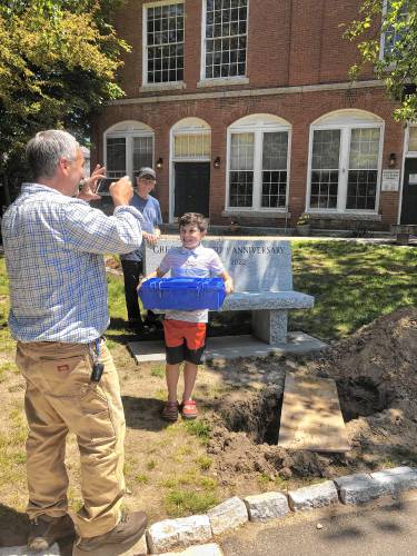 Luke Edgar, 8, of Greenville, prepares to bury a time capsule in front of the Town Hall and Chamberlin Free Library on Memorial Day.