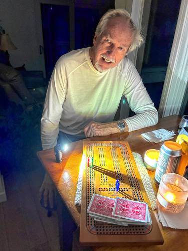 Warren Carlson plays cribbage after the power went out at his home in Dublin.