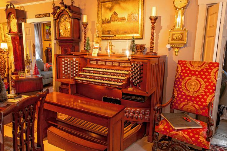 A grand organ for sale on the ground floor of Hayfields Antiques, flanked by ornate clocks and an antique chair.