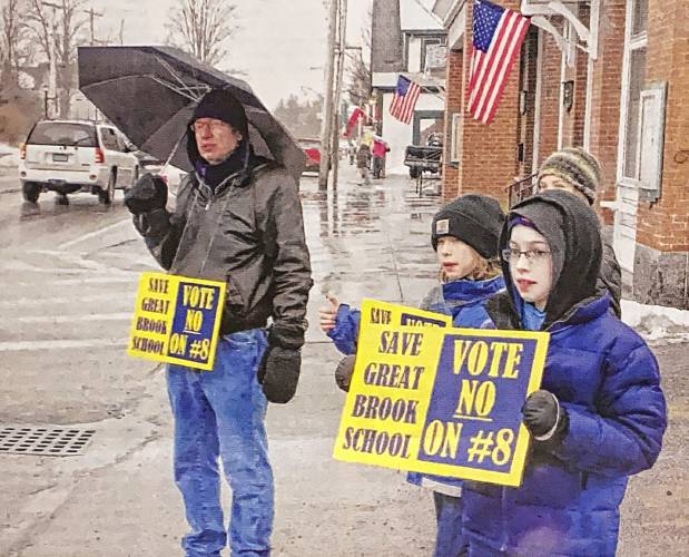 In 2013, Pete Burwen, left, stands outside of Antrim Town Hall, campaigning to save Great Brook School with his son Sean, right, and Nicholas Drummond, middle, who were both fifth-graders at GBS at the time.