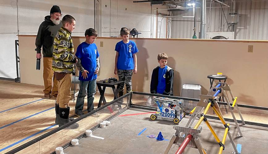 From left, coach Joe Ouellette, Malcolm Holt, Isaac Witham, Rowan Mair and George Parker test their robot in the competition field at MAXT Makerspace. 