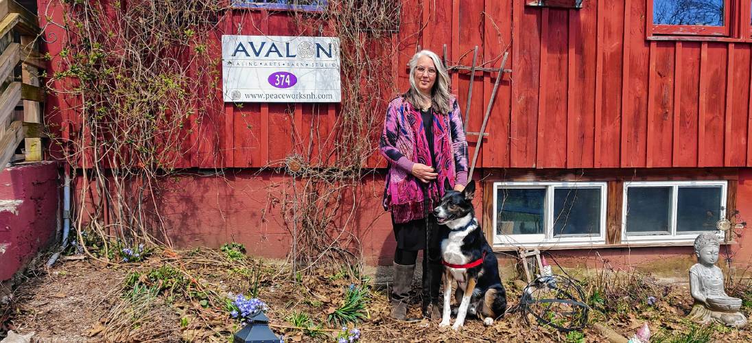 The Rev. Barbara Thorngren stands in front of her Avalon Healing Arts Barn Studio and Sanctuary with her dog Skylar.