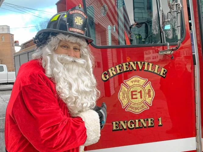 Jim Feldhusen, as Firefighter Santa, stands next to a Greenville fire truck.