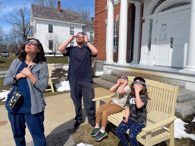 The Christensen family of Antrim watches the start of the eclipse at Tuttle Library. 
