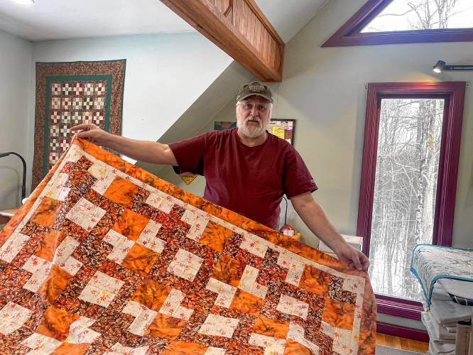 Scott Christophers of The Quilted Bug displays a finished quilt. 