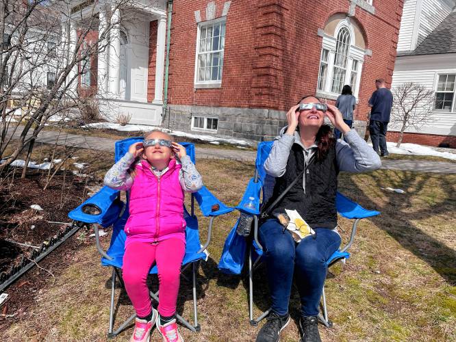 An Antrim mother and daughter spot the beginning of Monday’s solar eclipse. 